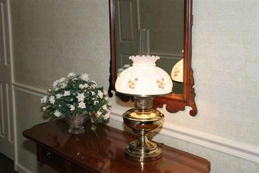 A lamp is sitting on a table next to a mirror and a vase of flowers.