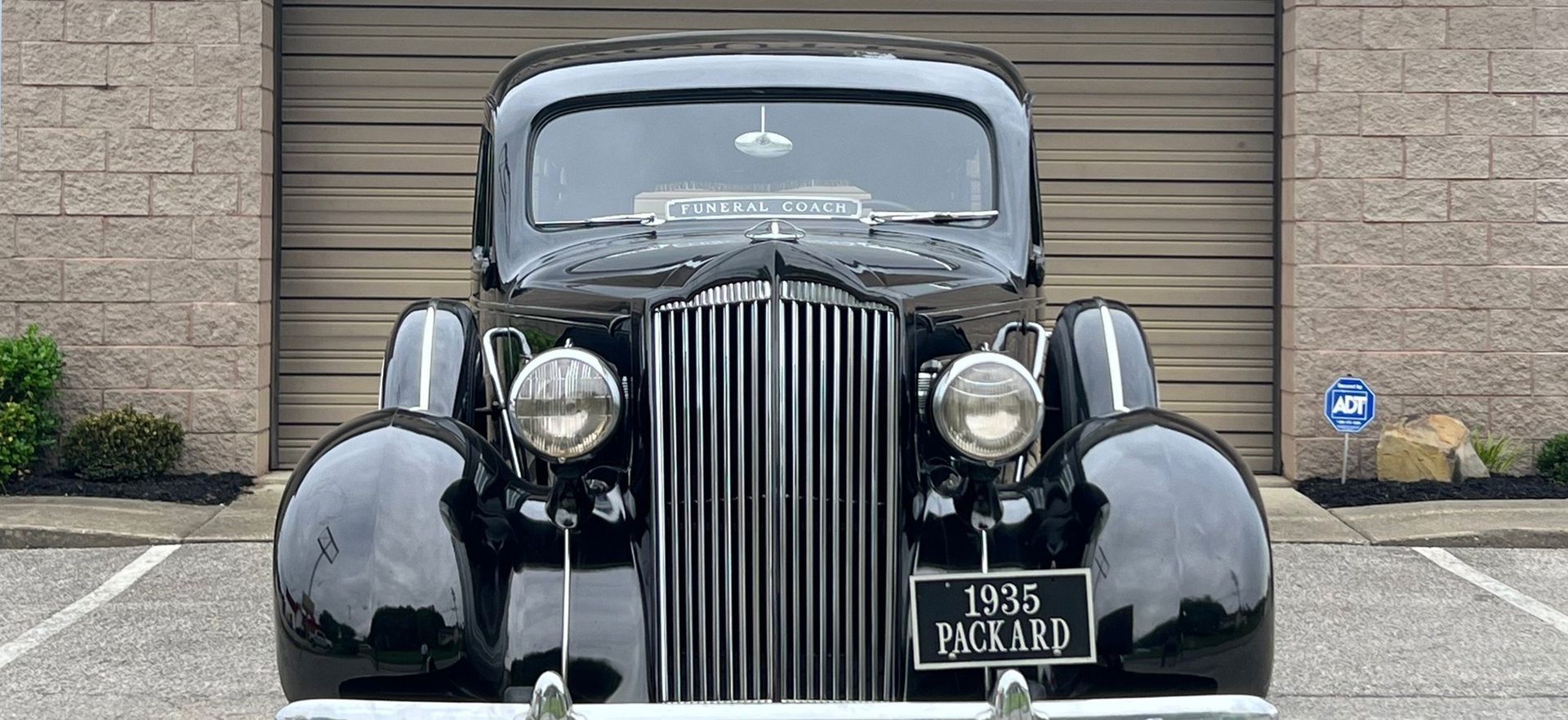 A black car is parked in a parking lot in front of a garage.