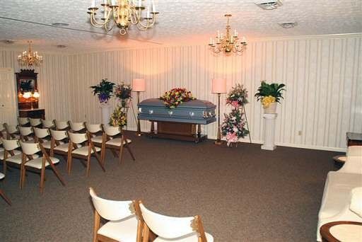 A room with a coffin and chairs in it