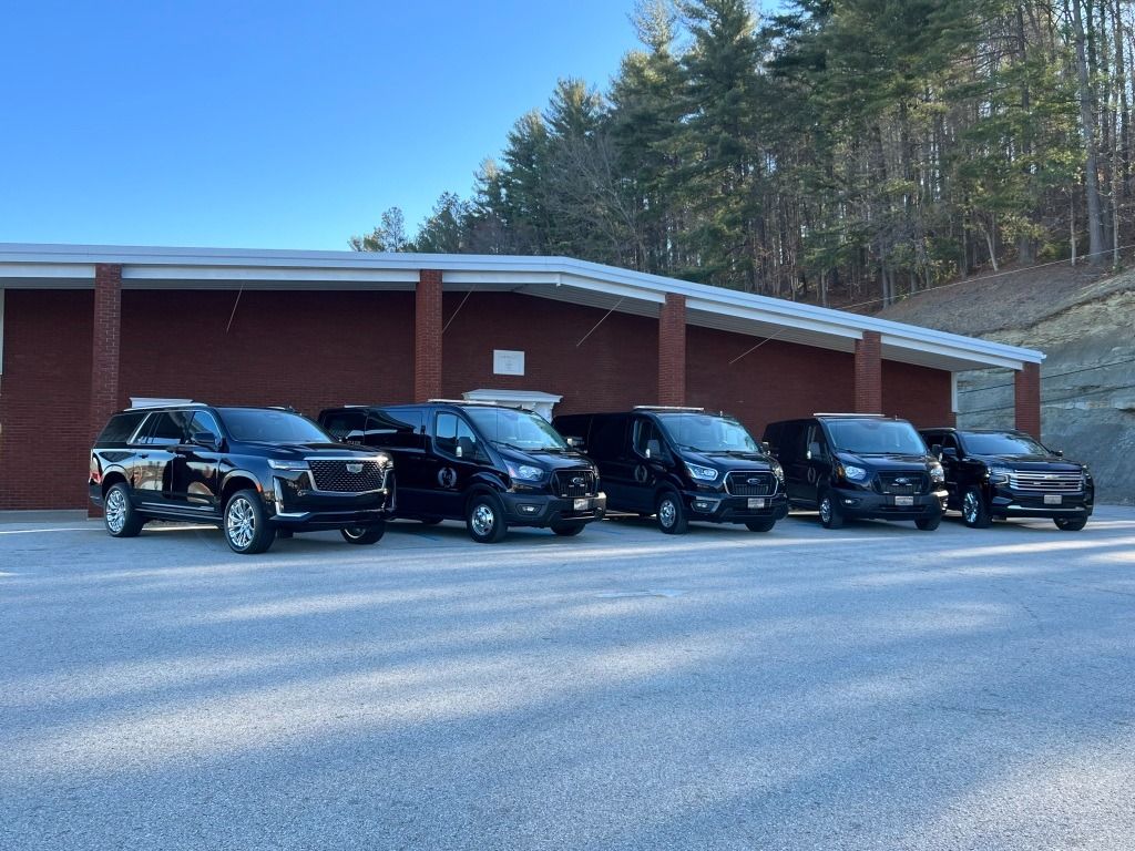 A row of black cars are parked in front of a building.