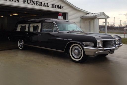 A black car is parked in front of a funeral home.