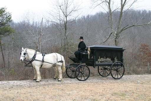 A man is riding a horse drawn carriage down a dirt road.