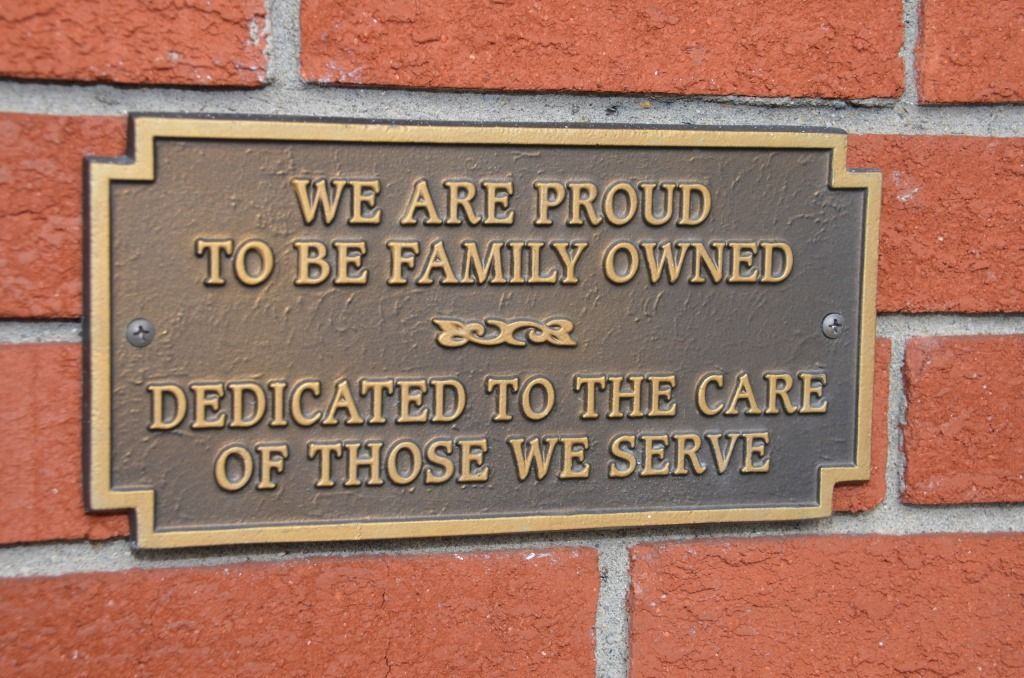A plaque on a brick wall that says we are proud to be family owned dedicated to the care of those we serve