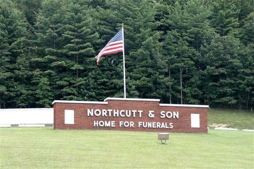 A sign for northcutt & son home for funerals with an american flag flying in the background.