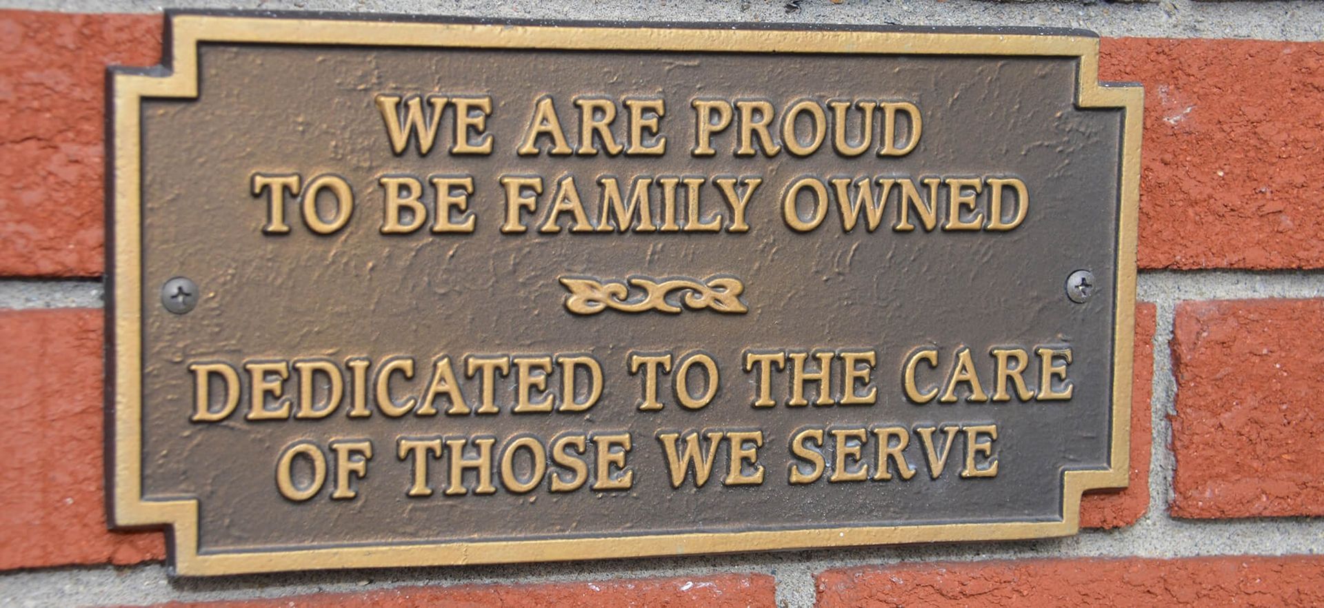 A plaque on a brick wall says we are proud to be family owned and dedicated to the care of those we serve