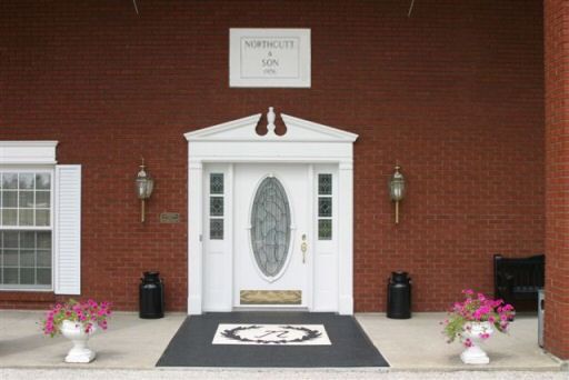 A brick building with a white door and a sign that says northcote & son