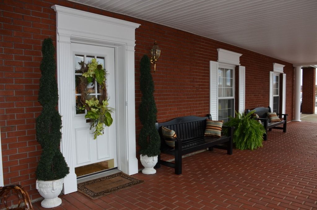 A porch with a bench and a wreath on the door