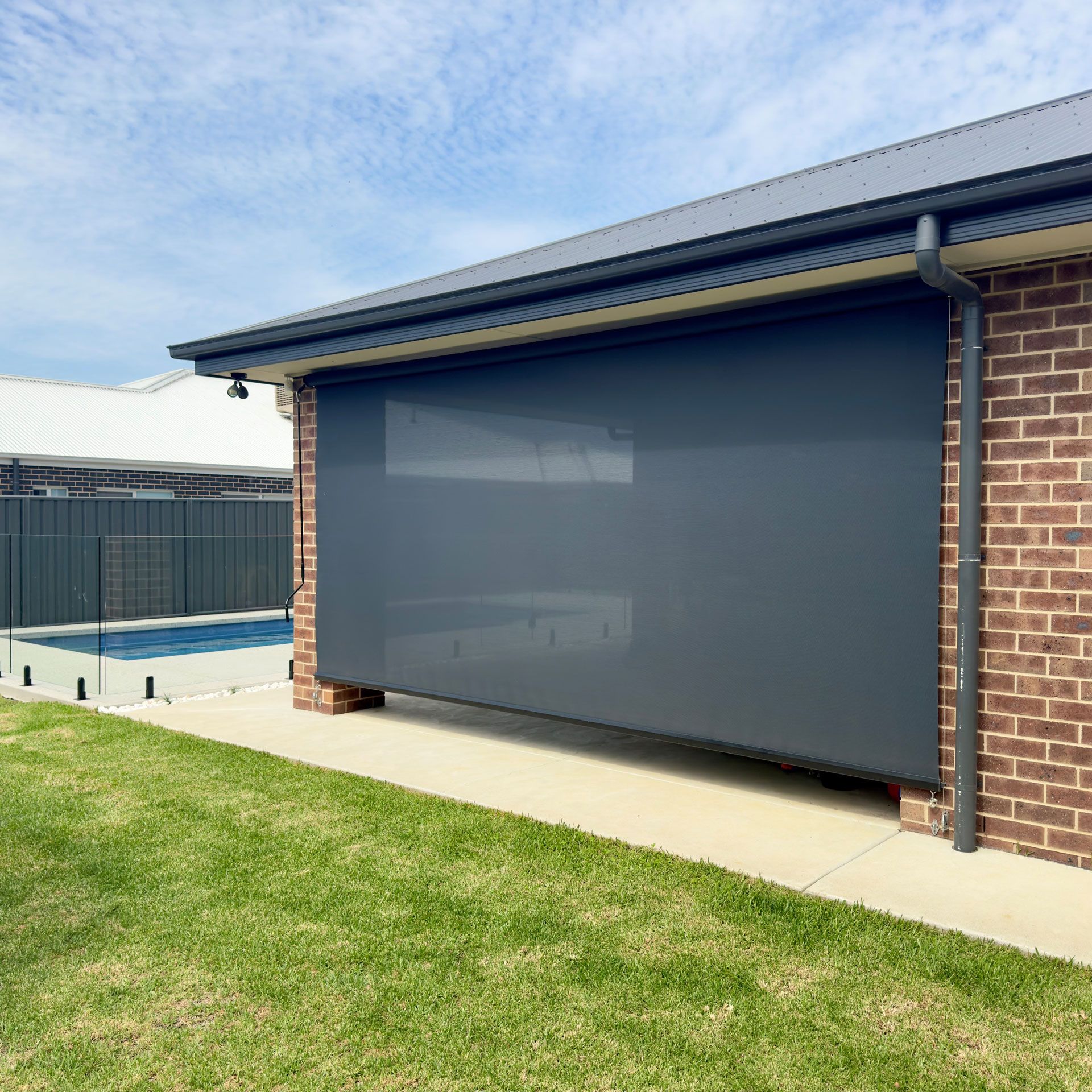 Wire guide awnings on the exterior of a home with a pool in the background