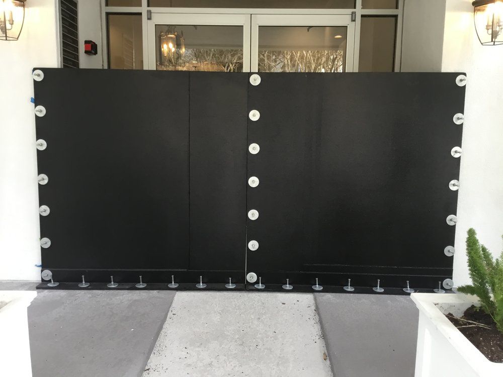 A black gate with white dots on it is in front of a building