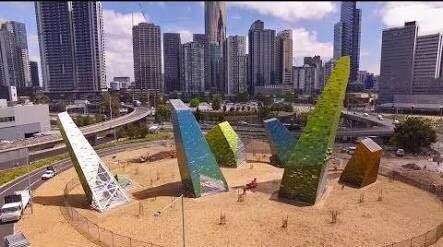An aerial view of a climbing wall in front of a city skyline.