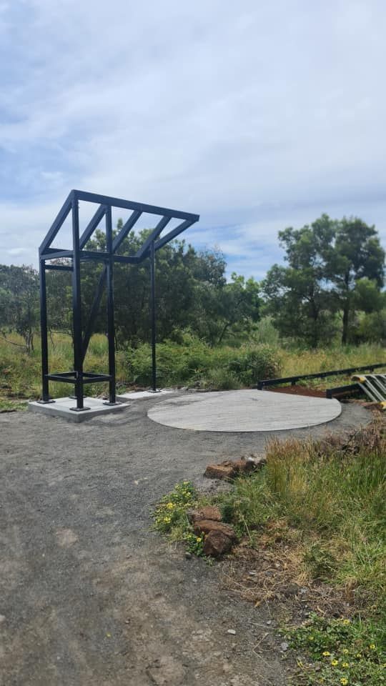 A metal structure is sitting on top of a dirt road in the middle of a field.