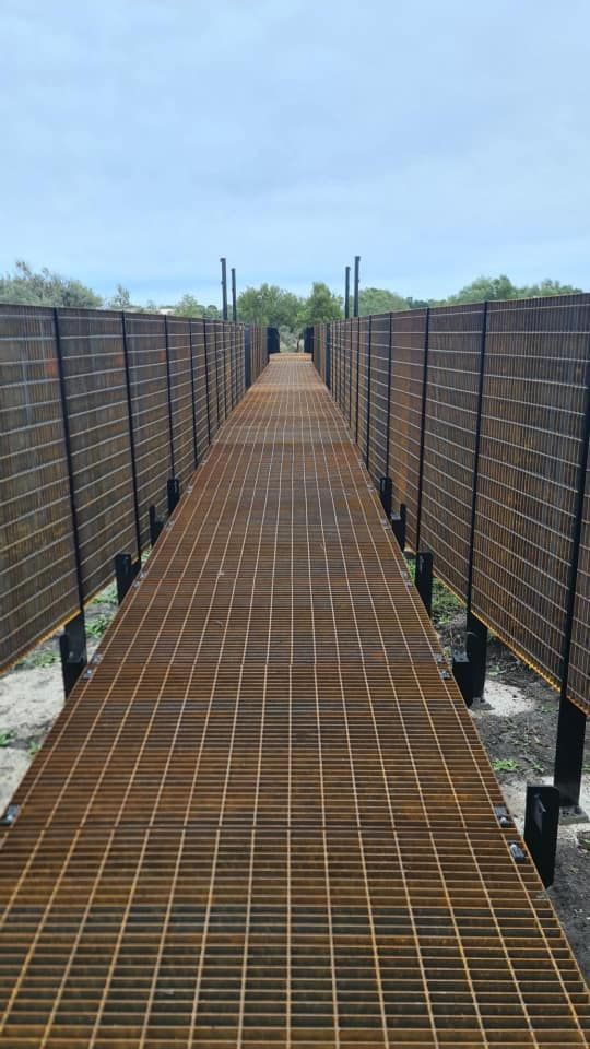 A long metal walkway with a fence along the side of it.