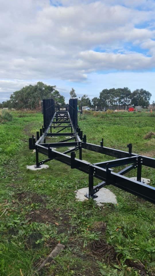 A large metal structure is sitting in the middle of a grassy field.