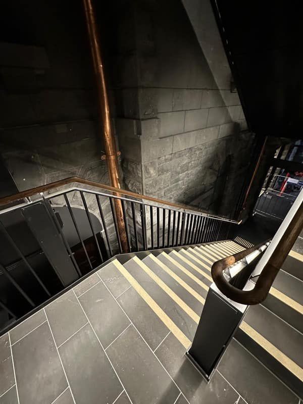 A staircase with a railing and a brick wall