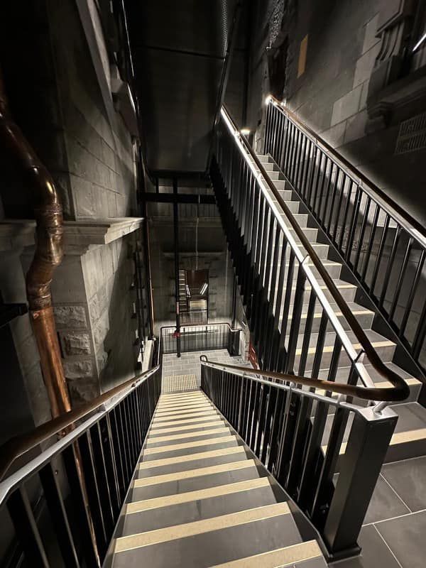A staircase with a railing going up and down in a dark room.