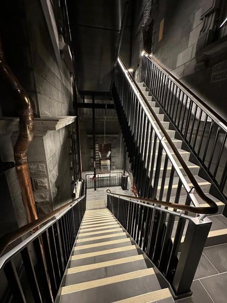 A staircase with a railing going up and down in a dark room.