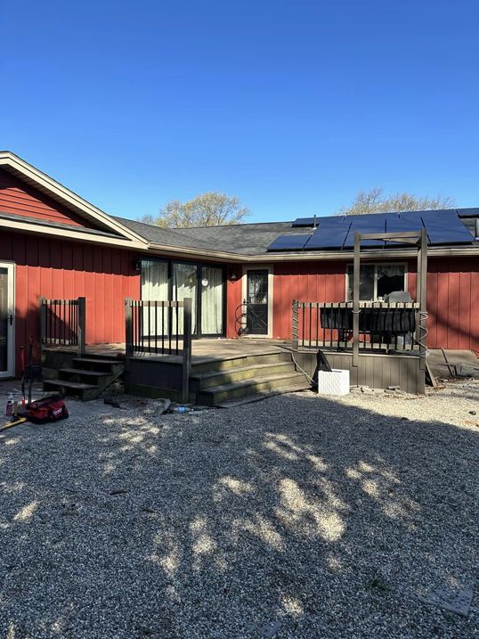 A red house with a deck and solar panels on the roof