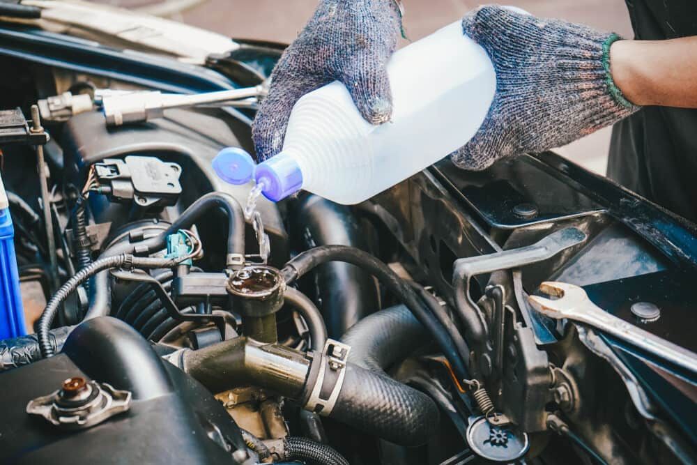 a Person is Pouring Water Into a Car Radiator — Wayne Boylett Mechanical In Bungalow, QLD