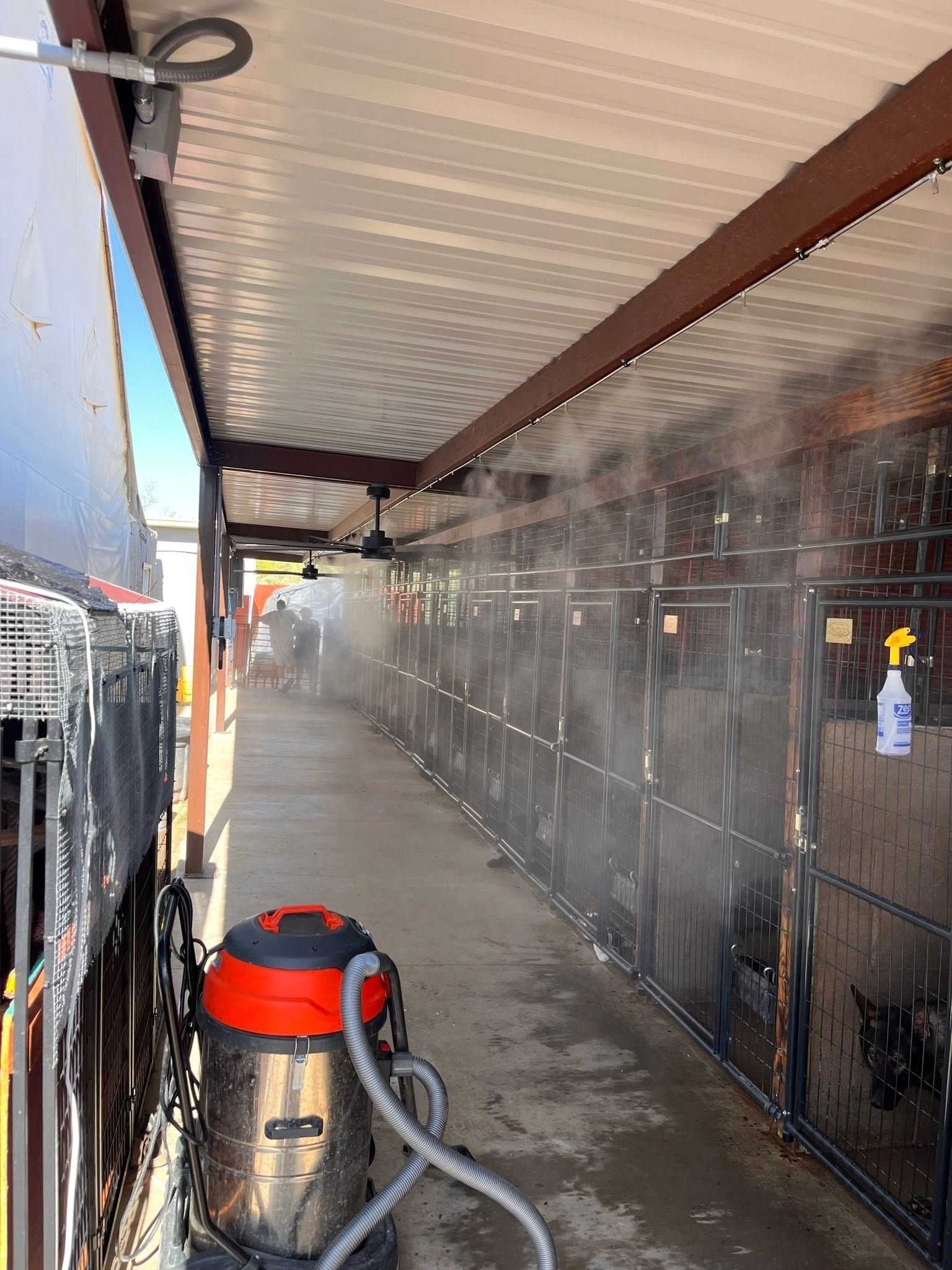 Narrow covered walkway with a wet floor, dark wall panels, and a wet/dry vacuum in the foreground.