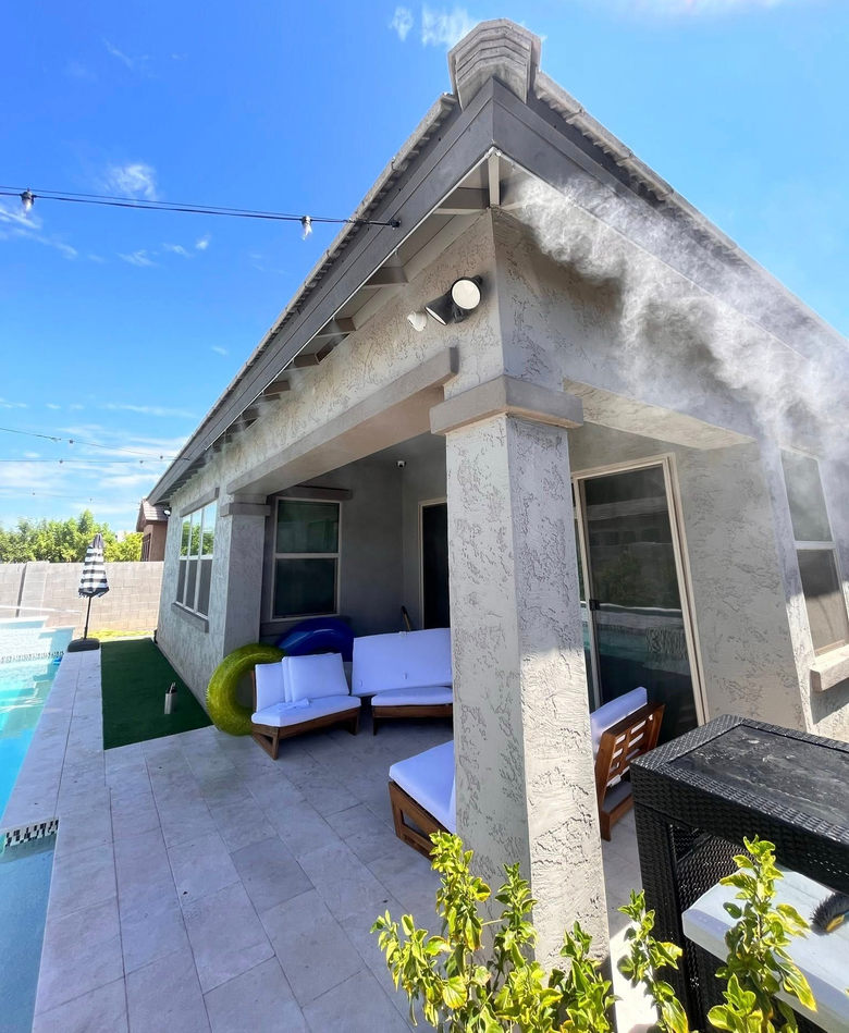 Modern house patio with white sofa, tiled floor, and a pergola under a bright blue sky.