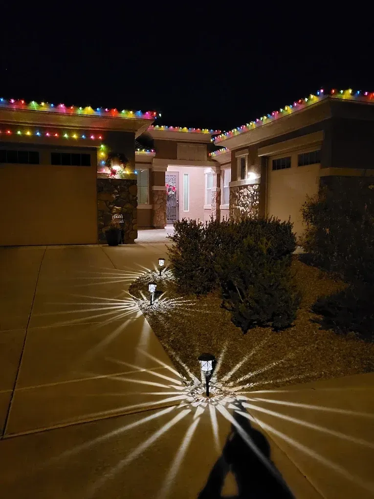 House entrance at night with colorful string lights and solar path lights illuminating the walkway