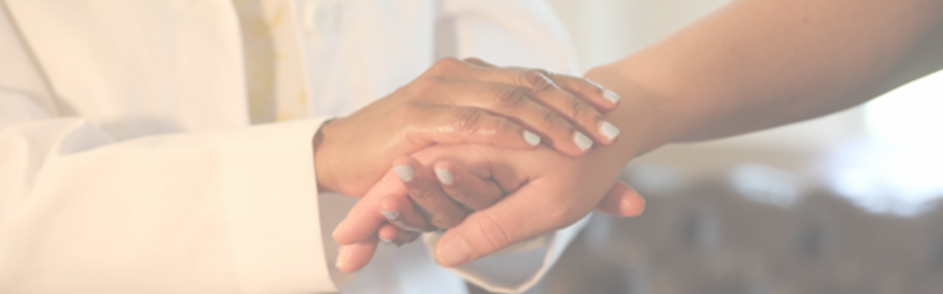 Two hands clasped in a supportive gesture against a soft blurred background