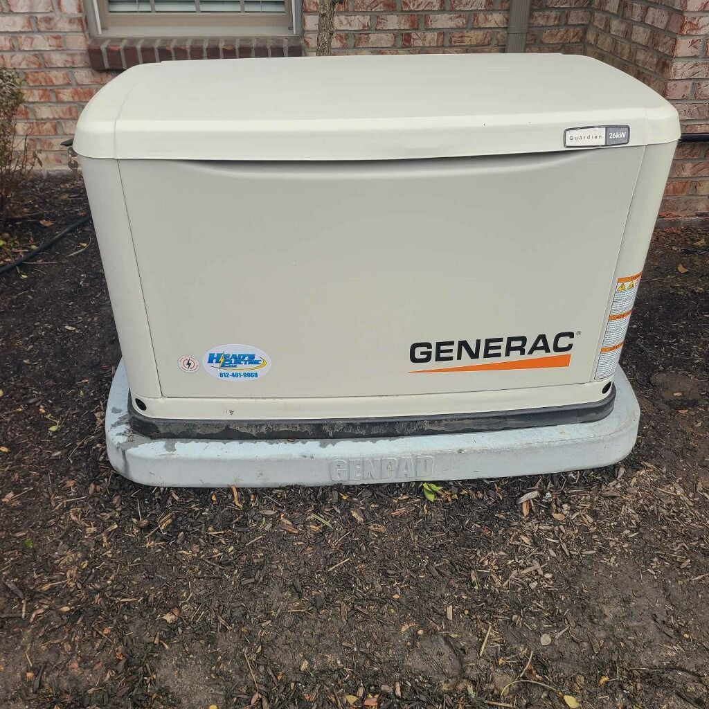 Generac generator on a concrete pad next to a brick wall and a window.