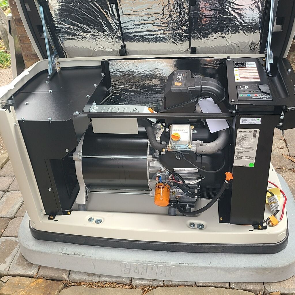 A generator with open cover, showing engine components and control panel. Beige and black, outdoors.