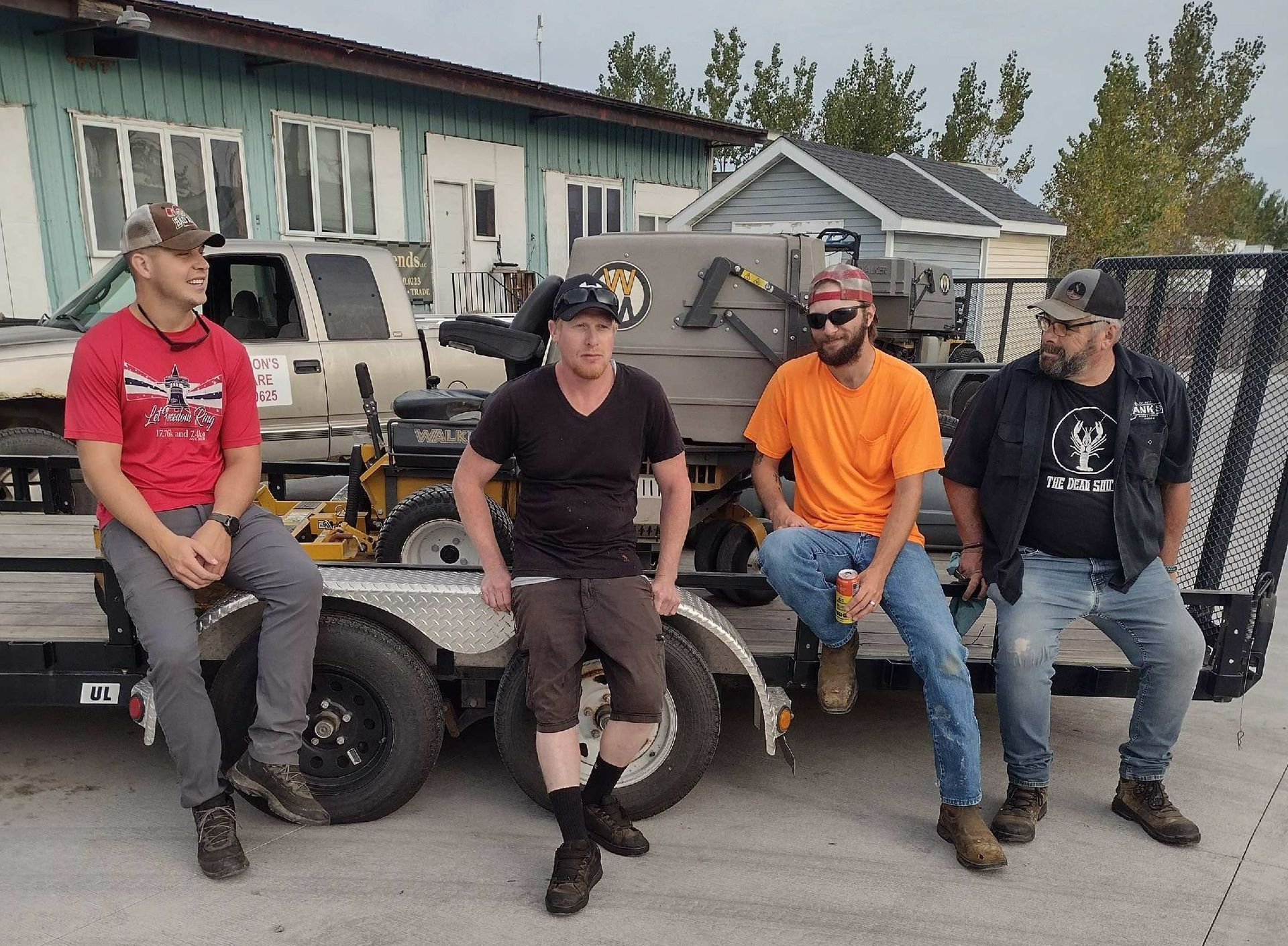A group of men are sitting on the back of a trailer. A group of men are sitting on the back of a trailer.