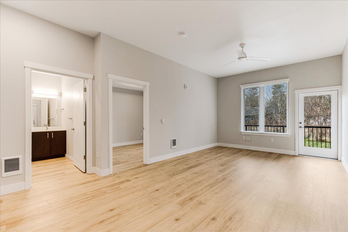 an empty living room with hardwood floors and a ceiling fan .