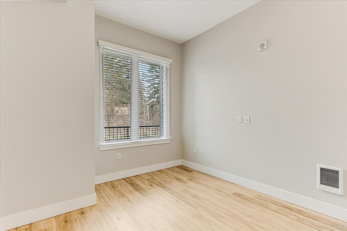 an empty room with hardwood floors and two windows .