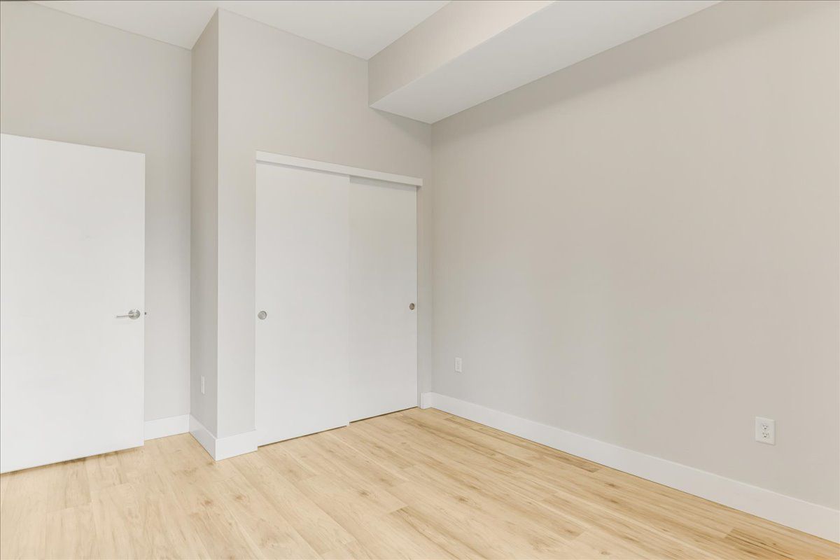 an empty bedroom with hardwood floors and white walls .