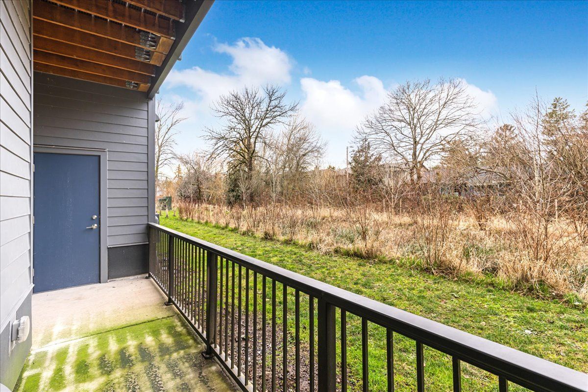 a balcony with a metal railing overlooking a grassy field .