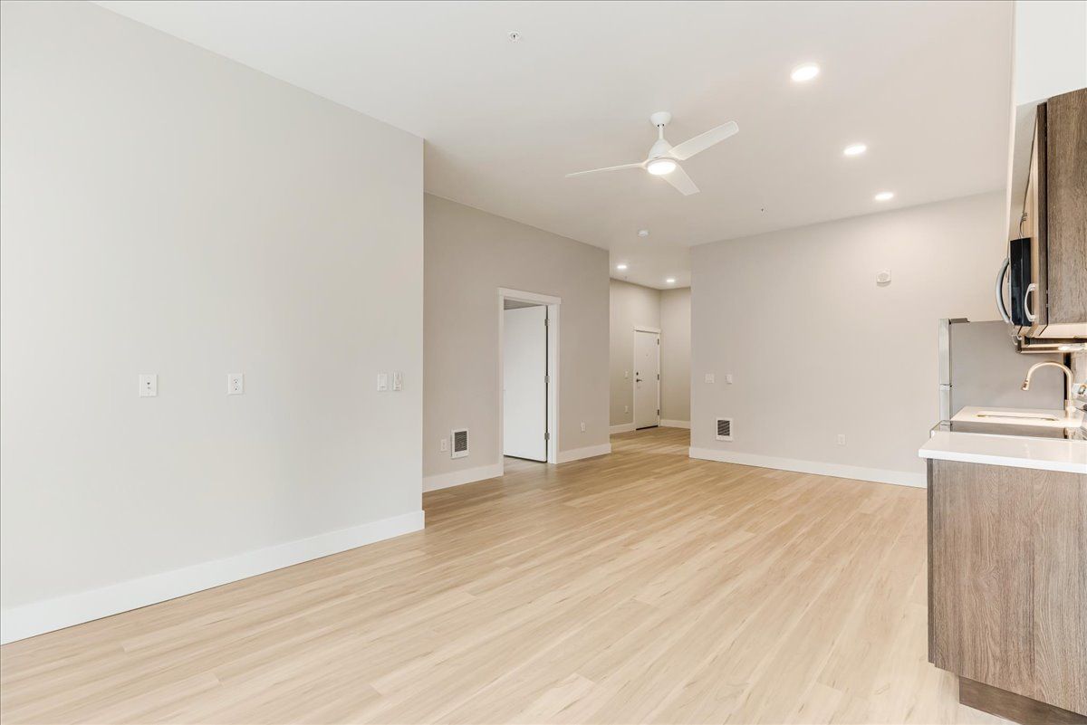 an empty living room with hardwood floors and a ceiling fan .
