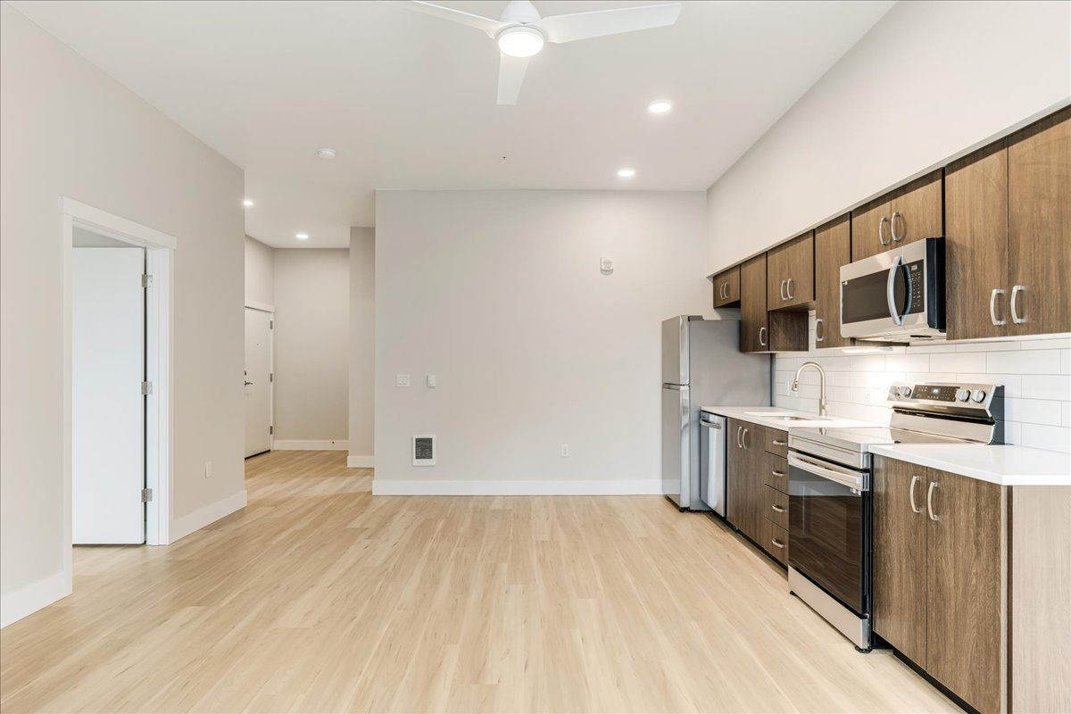 an empty kitchen with stainless steel appliances and wooden cabinets