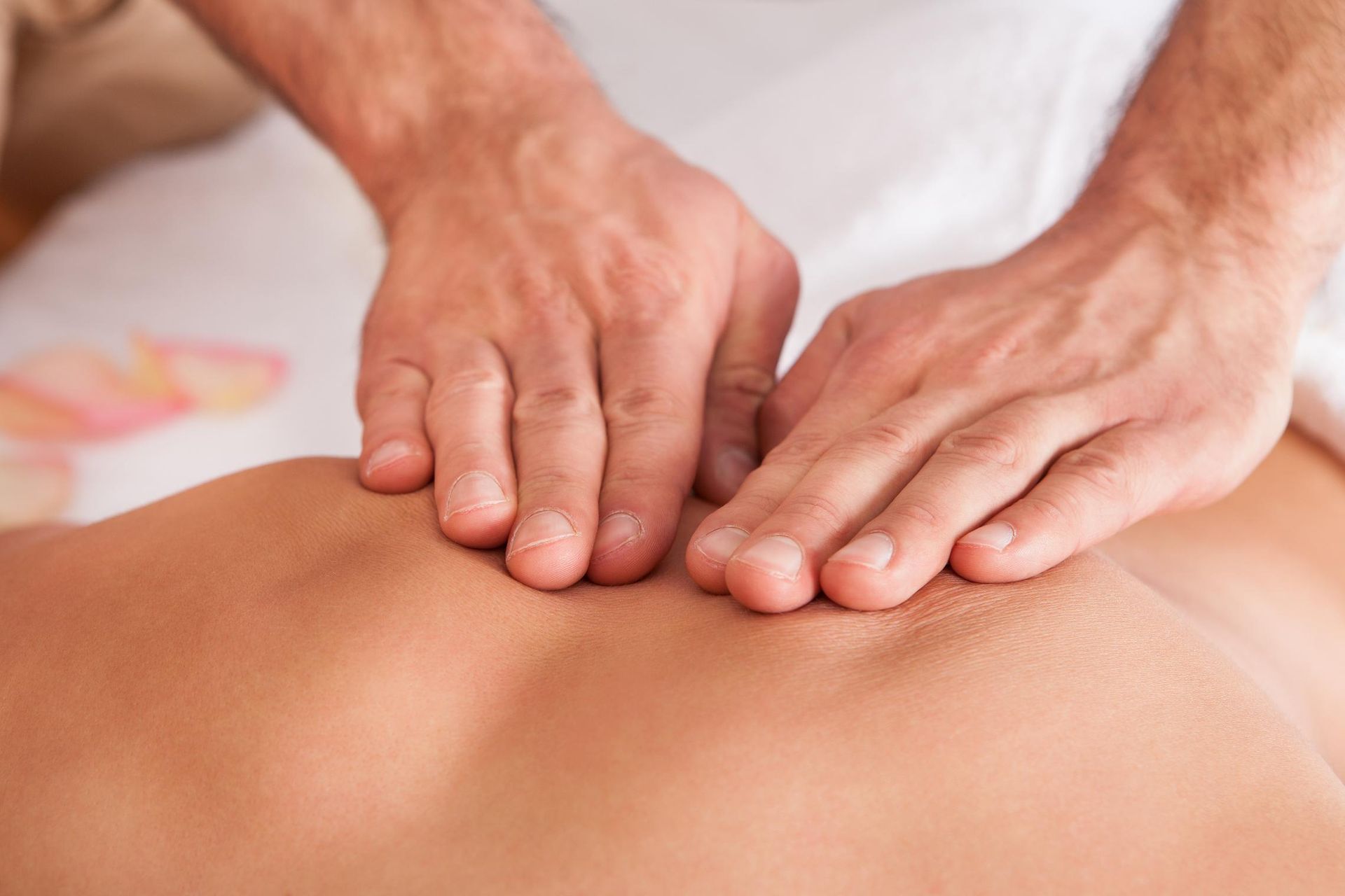 Hands massaging a person's bare back; light skin, close-up.