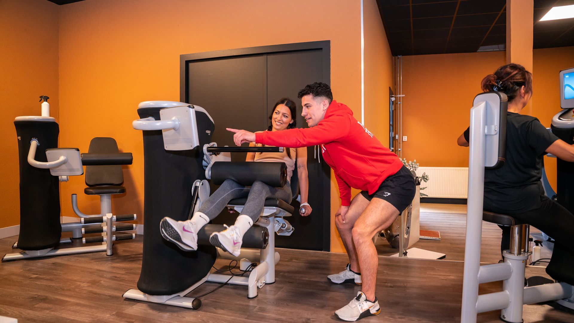 Een man en een vrouw zitten op een fitnessapparaat in de sportschool.