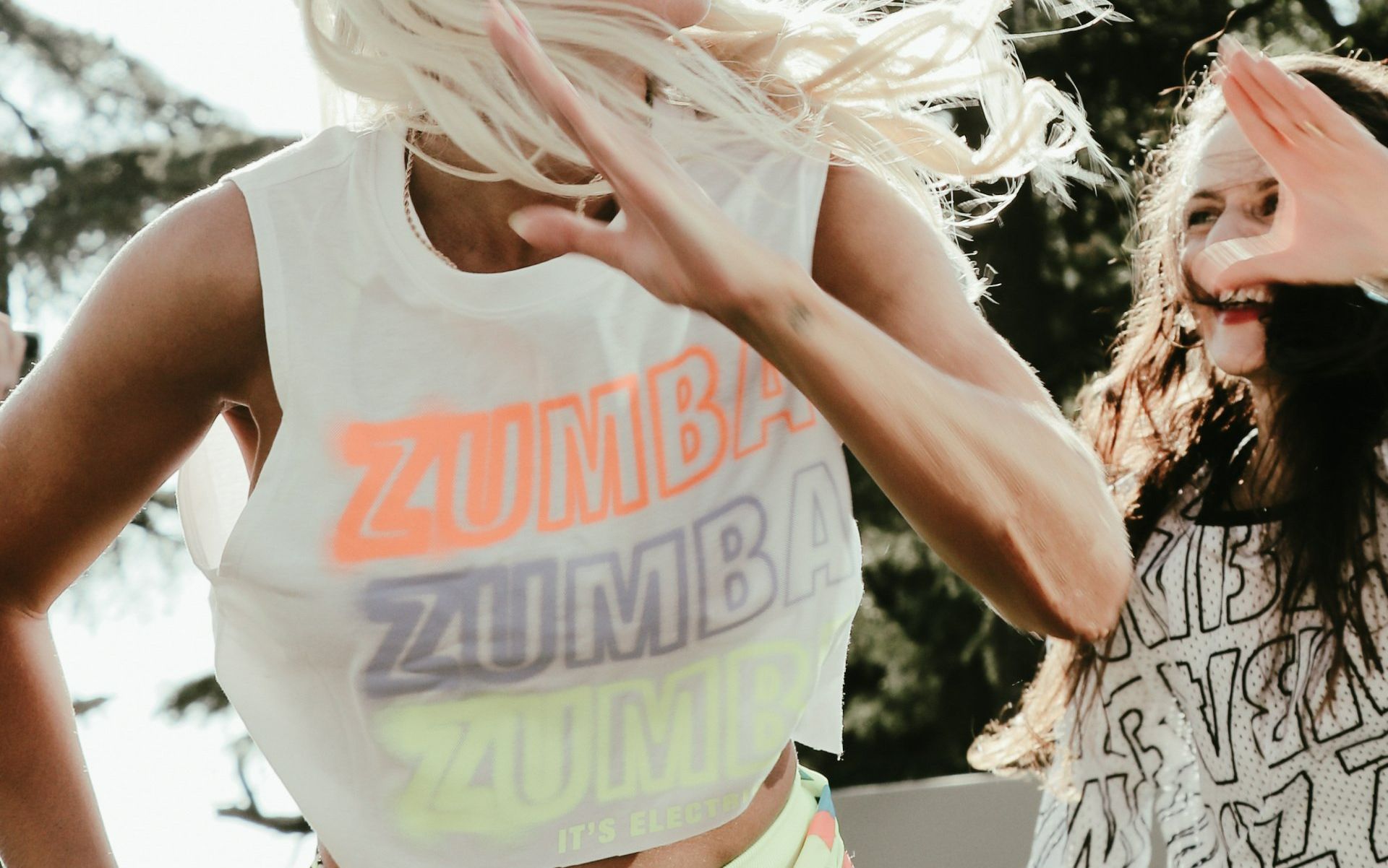 Een vrouw die een zumba-shirt draagt, danst met een andere vrouw.