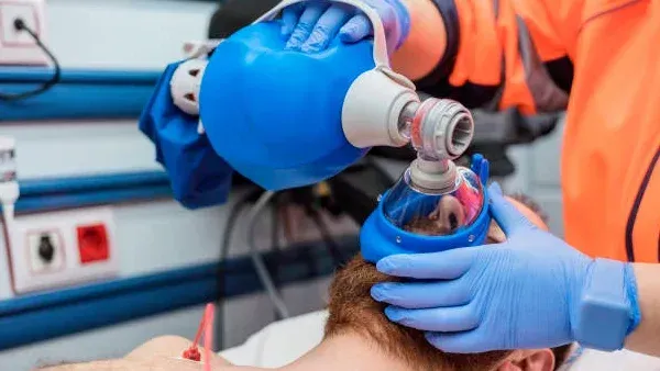 Healthcare worker using a bag-valve mask on a patient in a hospital setting