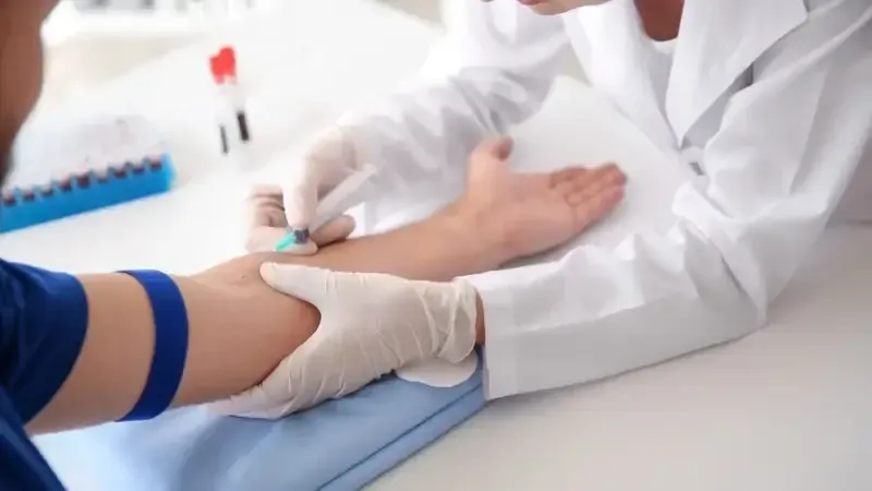 Doctor taking a blood sample from a patient’s arm in a clinic.