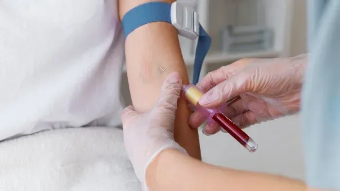Blood sample being drawn from a patient’s arm with a syringe in a clinical setting
