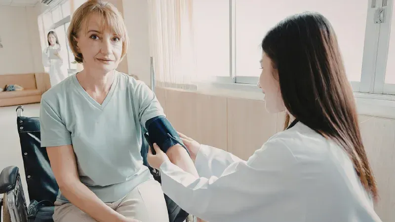 Nurse taking a woman’s blood pressure in a bright clinic room