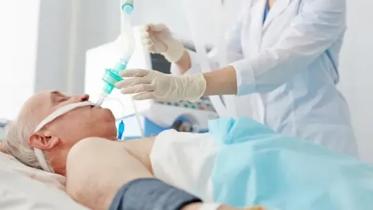 Medical worker performing a nasal swab on a patient lying in a hospital bed