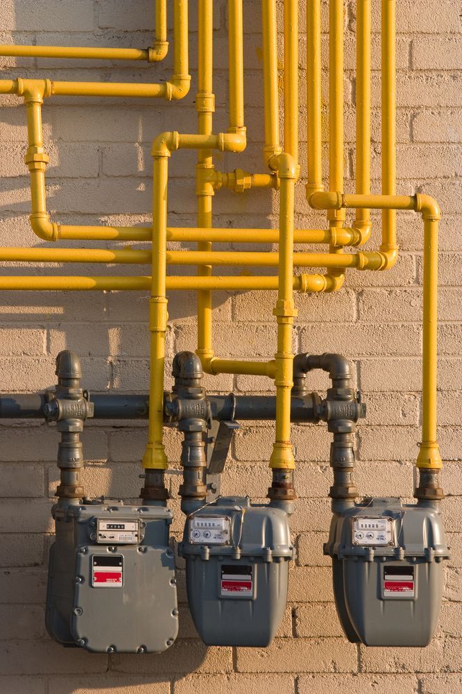Three Gas Meters Are Attached to a Brick Wall — Pimlico Plumbing in Mount Louisa, QLD