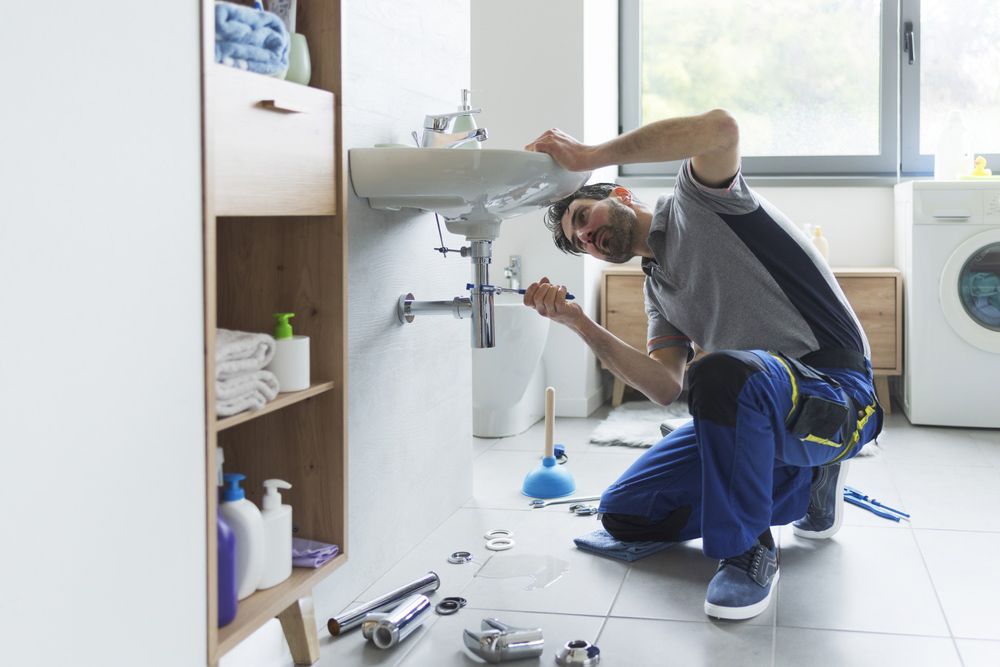 A Plumber is Fixing a Sink in a Bathroom — Pimlico Plumbing in Mount Louisa, QLD