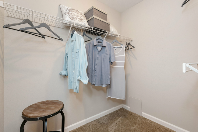 A walk in closet with clothes hanging on the wall and a stool at Steeplechase Apartments in Knoxville, Tennessee