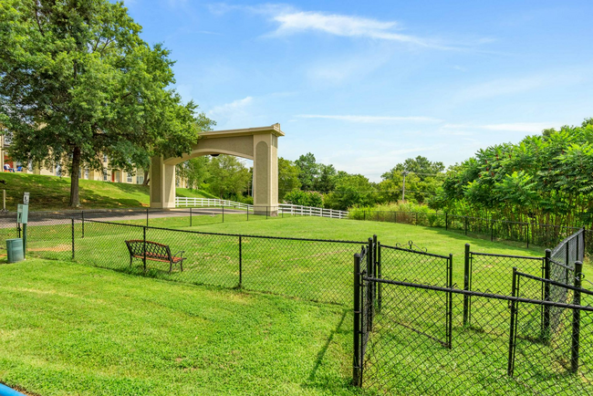 A dog park with a chain link fence and a bridge in the background at Steeplechase Apartments in Knoxville, Tennessee