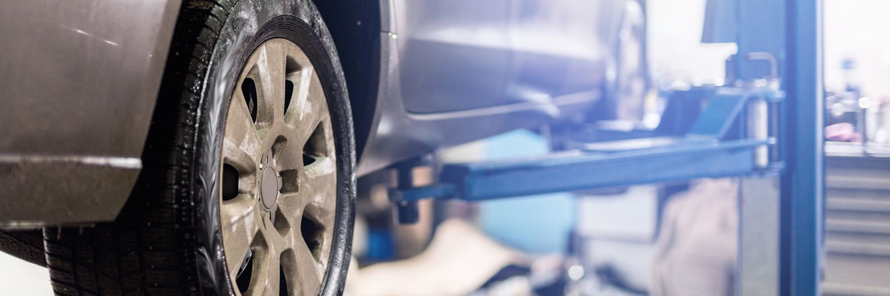 A car is sitting on a lift in a garage.