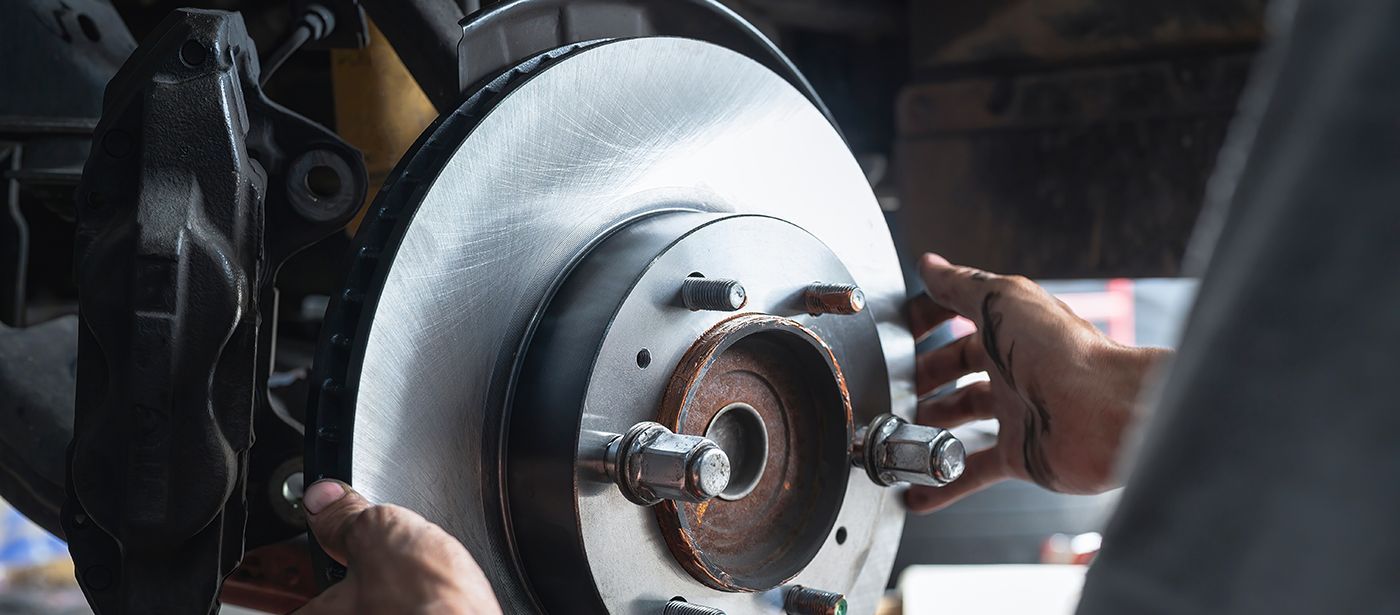 Hands working on a car brake rotor. A person is installing the brake rotor.