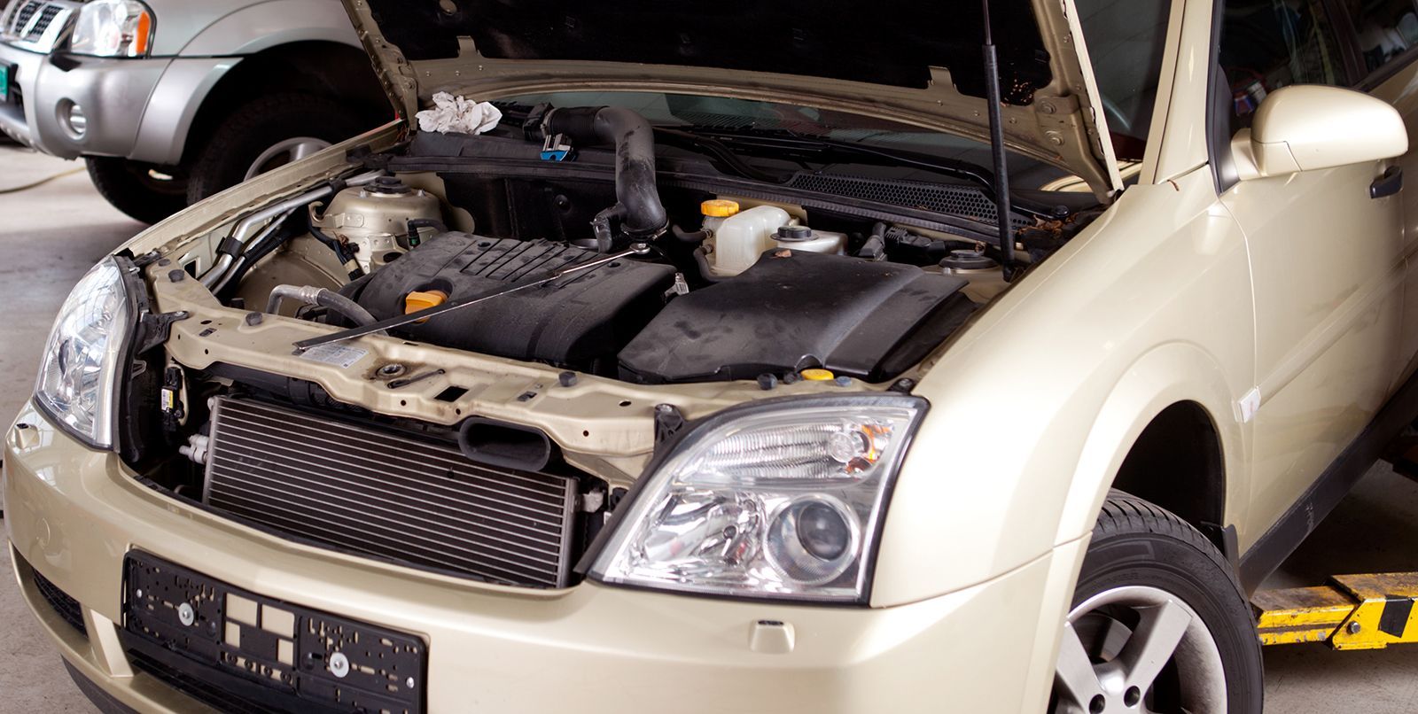 a car with the hood open is sitting on a lift .